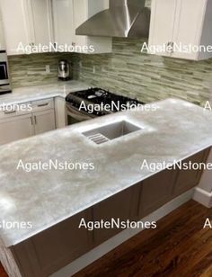 a kitchen with white cabinets and marble counter tops