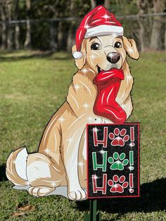 a dog with a santa hat and scarf is sitting on a sign in the grass