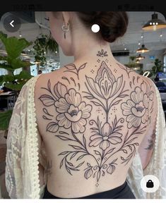 the back of a woman's upper body with flowers on her left and right side