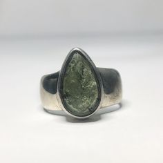 This genuine moldavite ring weighs 8.5 grams and is a size US 7.75. This rare stone sits in all sterling silver, the front is faceted and the back is raw. Our Moldavite is guaranteed 100% genuine from the Czech Republic. Moldavite comes from a meteor collision with Earth almost 15 million years ago. Found only in the Czech Republic these green Gems are one of the most rare minerals on Earth. This tektite is composed of natural glass and is created when a meteorite collides with earth resulting i Classic Teardrop Gemstone Rings, Modern Teardrop Jewelry With Bezel Setting, Modern Teardrop Gemstone Rings, Teardrop Ring With Natural Inclusions For Gift, Teardrop Gemstones For Anniversary, Unique Silver Pear-shaped Rings, Modern Pear-shaped Gemstone Ring, Handmade Silver Pear-shaped Rings, Silver Teardrop Emerald Ring Gift