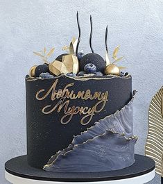 a black and gold birthday cake with blueberries on top