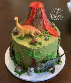 there is a cake that looks like a volcano and some dinosaurs on the top of it