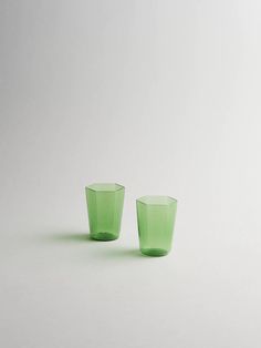 two green cups sitting next to each other on a white surface with no one around them