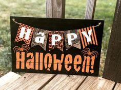 a sign that says happy halloween hanging on a wooden chair in front of some grass