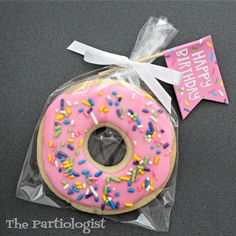 a pink frosted donut with sprinkles and a happy birthday sign