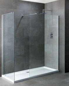 a glass shower door in a bathroom with tile walls and grey flooring on the wall