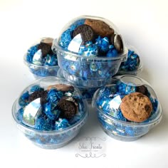 four plastic containers filled with cookies and blue candies