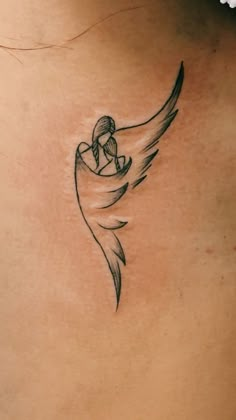 the back of a woman's neck with a small angel tattoo on her left side