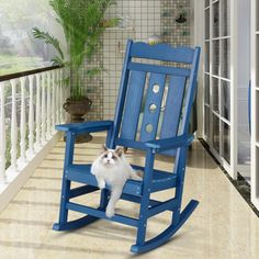 a blue rocking chair with a cat sitting on it's back in front of a porch