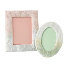 a pink and white photo frame next to a small round mirror on a white background