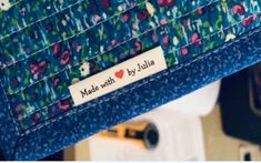 a close up of a blue bag with flowers on it and a name tag that says made with love by julia