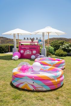 an inflatable pool is set up on the lawn with umbrellas over it