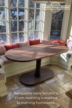 a table sitting in the middle of a room next to a window with pillows on it