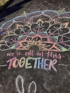 chalk drawing on the ground with words written in it and an umbrella above them that says, we are all here together