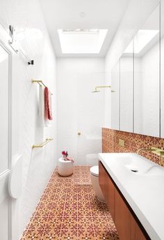 the bathroom is decorated in white and orange tile, with gold accents on the walls