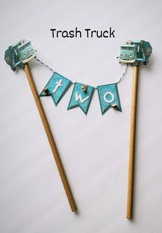 there are two wooden sticks that have decorations on them and the words trash truck spelled out