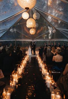 a bride and groom are standing under a tent with candles in front of the aisle