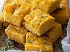 there are many squares of food in the tray on top of each other and sprinkled with rosemary