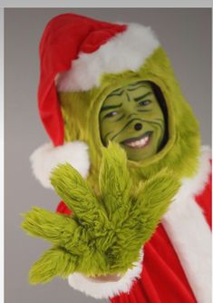 a man dressed as the grinch is holding his hand up