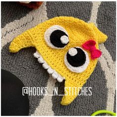 a crocheted yellow hat with black eyes and a red bow