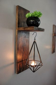 a wooden shelf with a candle holder and some plants on it, hanging from the wall