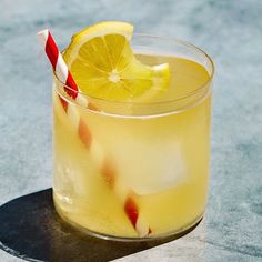 a glass filled with lemonade sitting on top of a table next to a red and white striped straw