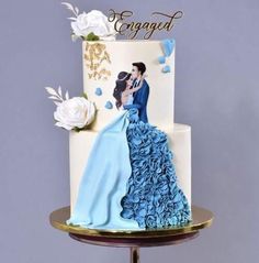 a white and blue wedding cake with an image of a bride and groom on top