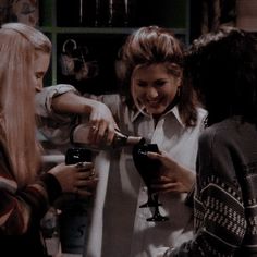 three women are standing together and one is holding a hair dryer in her hand