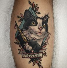 a black and white cat with a knife in its mouth tattoo on the leg, which reads moose