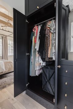 an open closet with clothes hanging on hangers and other items in the room next to it