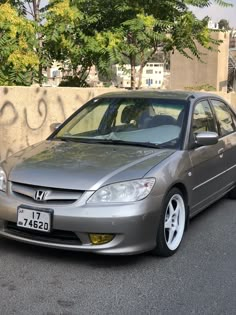 a silver car parked in front of a wall with graffiti on it's side