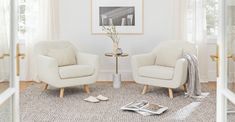 two white chairs sitting next to each other on top of a rug in a living room