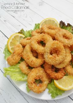 fried calamari on a plate with lettuce and lemon wedges