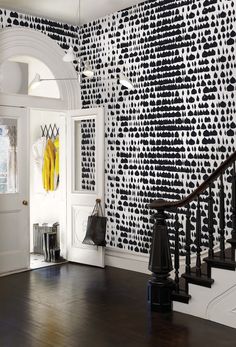 an entryway with black and white wallpaper, wood flooring, and stairs