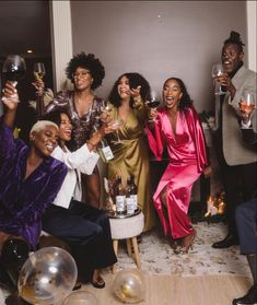 a group of people standing around each other with wine glasses in their hands and laughing