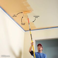 a man is painting the ceiling with paint rollers and a mop in his hand