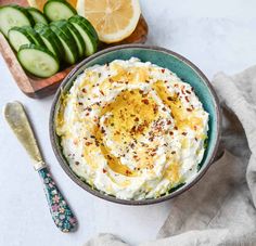 a bowl filled with cucumber and cheese on top of a table