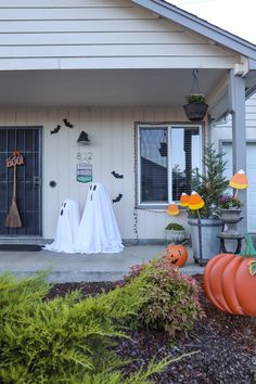 two halloween decorations in front of a house with pumpkins and ghost heads on the porch