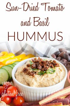 sun dried tomato hummus in a white bowl surrounded by fresh vegetables and other ingredients