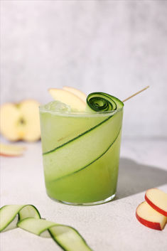 an apple and cucumber drink is garnished with a green twister