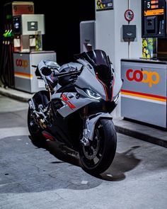 a motorcycle parked in front of a gas pump at night with no one around it