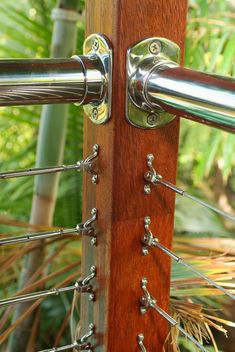 a close up of a metal handle on a wooden pole with plants in the background