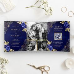 a blue and gold wedding card with two photos on it, next to some flowers