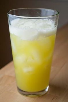 a glass filled with liquid sitting on top of a wooden table