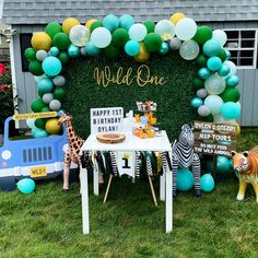 an outdoor birthday party with balloons, decorations and giraffes on the grass