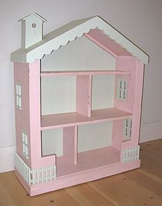 a pink doll house sitting on top of a wooden floor next to a white wall