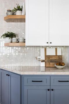 a kitchen with white cabinets and blue counter tops, along with wooden shelves above the sink