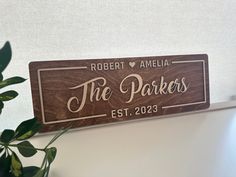 a wooden sign that says the parkers on it next to a potted plant