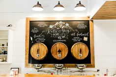 a chalkboard with three wooden barrels on it in front of a kitchen counter top