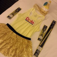 a yellow top and gold sequin skirt are sitting on a white bed with skis next to it